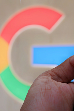 The Google logo and a hand holding a smartphone with Google Gemini on screen.